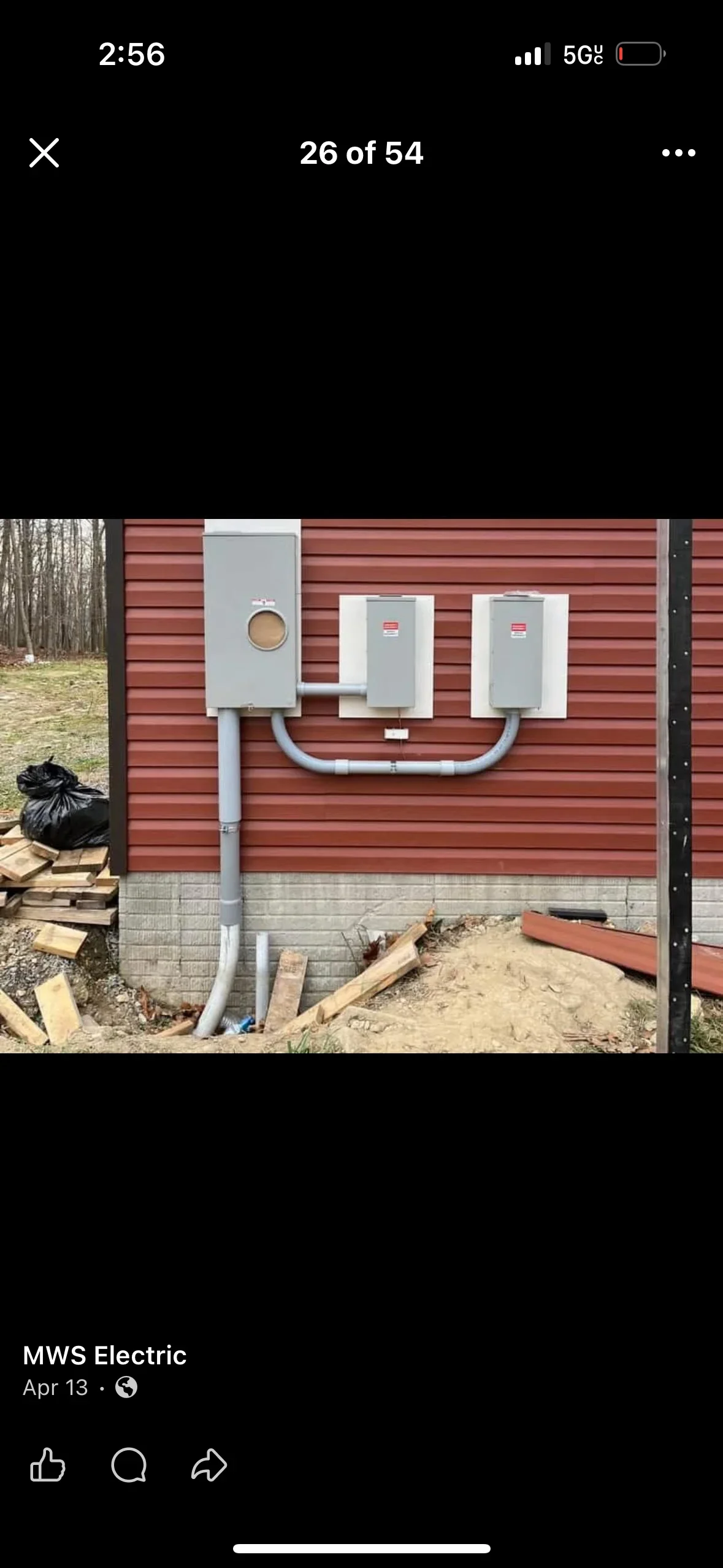 Main electrical panel and two EV chargers mounted on red metal siding with gray PVC conduit