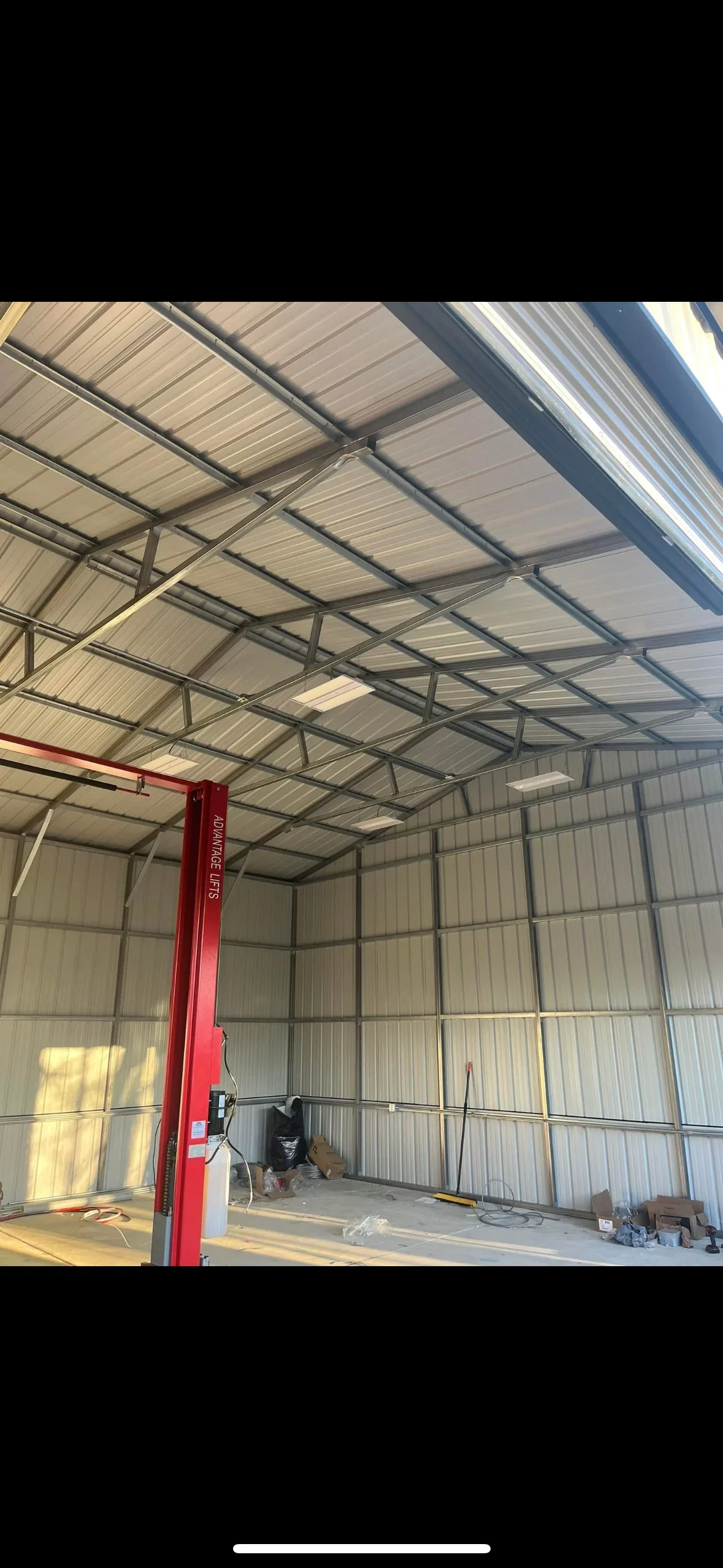Metal building interior with steel frame, corrugated walls, and red electrical column with conduit installation