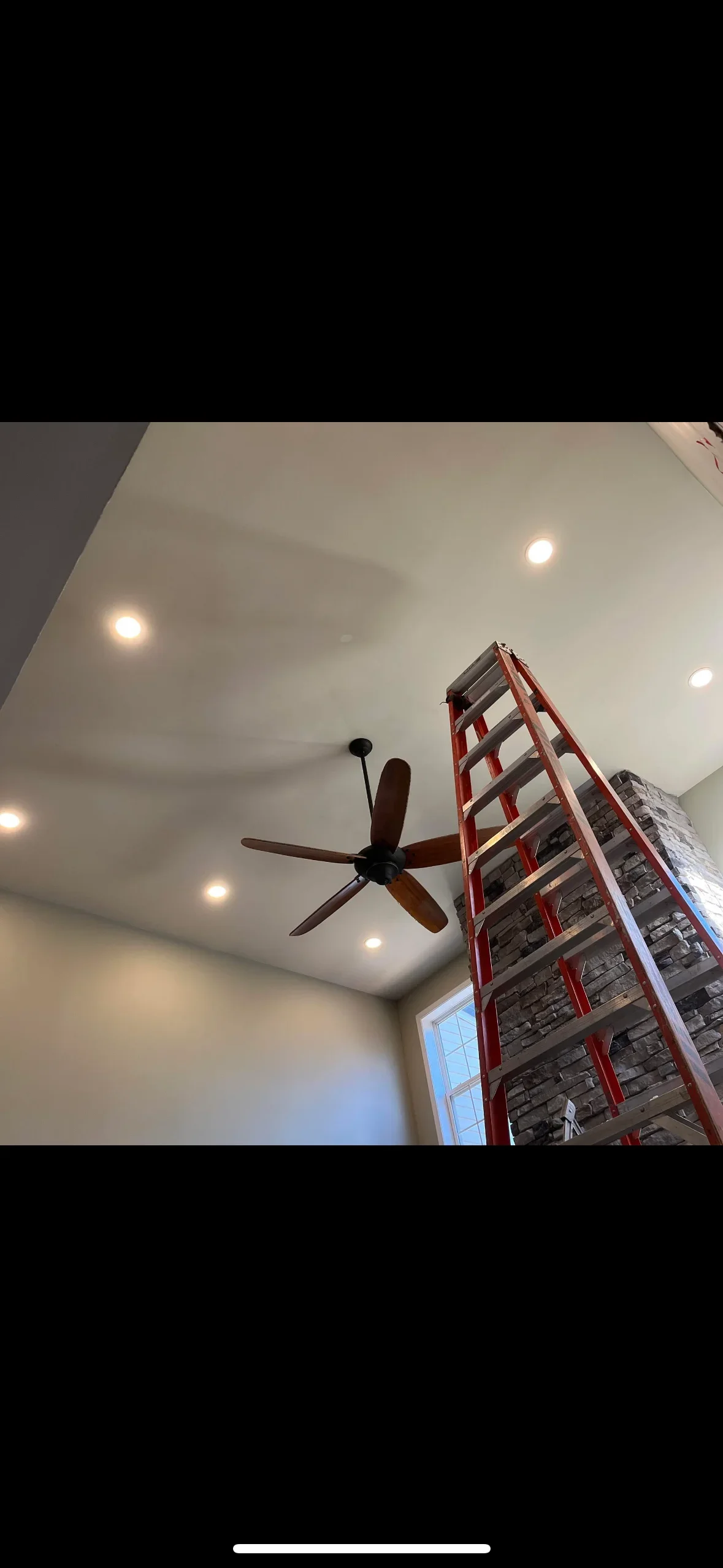 Recessed LED ceiling lights installed in drywall with ceiling fan and ladder visible