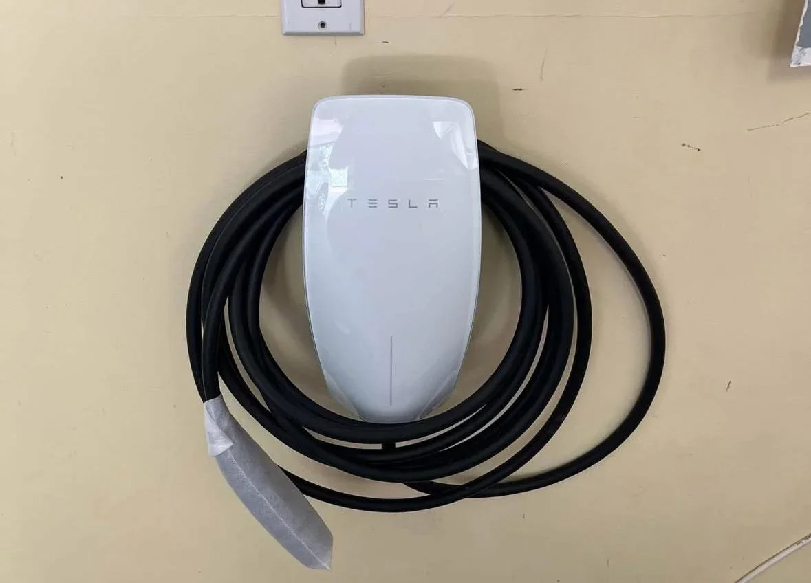 Tesla Wall Connector with black charging cable mounted on beige wall
