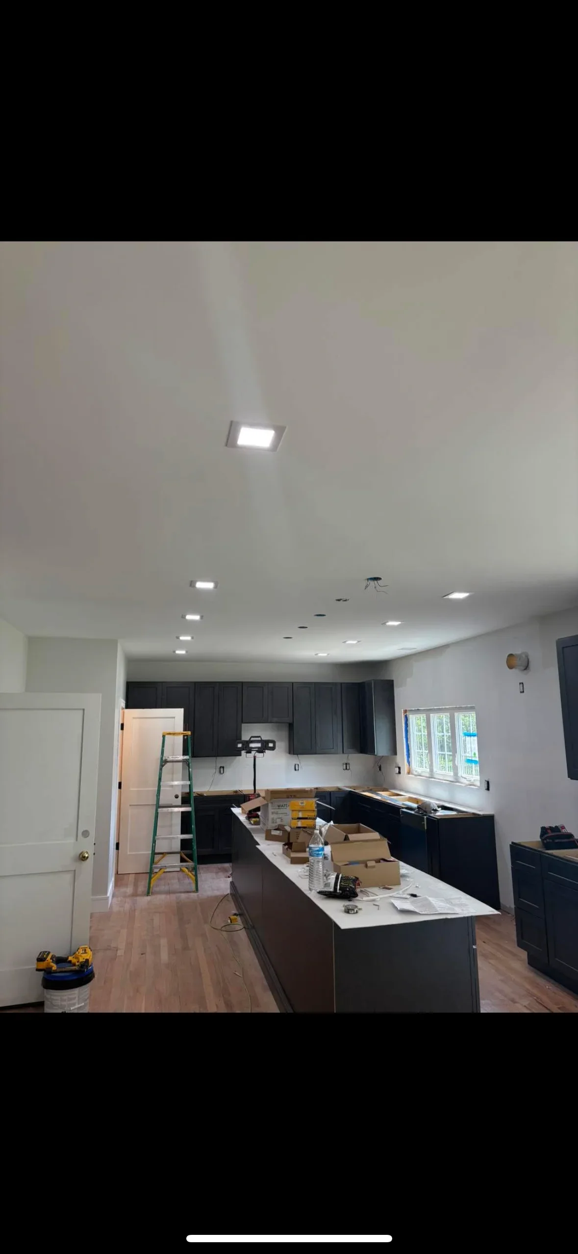 Recessed LED ceiling lights installed in kitchen with black cabinetry and white countertops