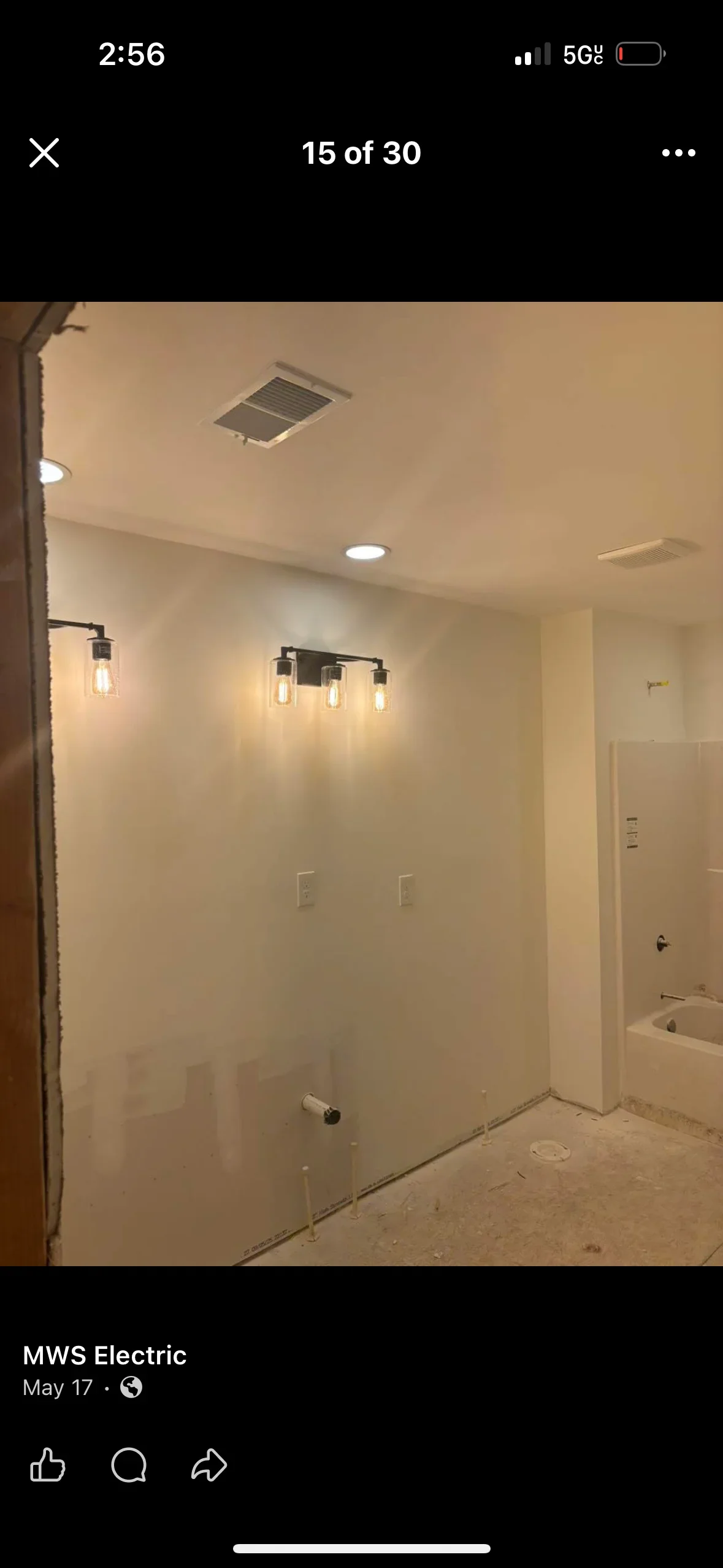 Bathroom with recessed ceiling lights, black vanity fixture with glass shades, and electrical outlets installed in drywall